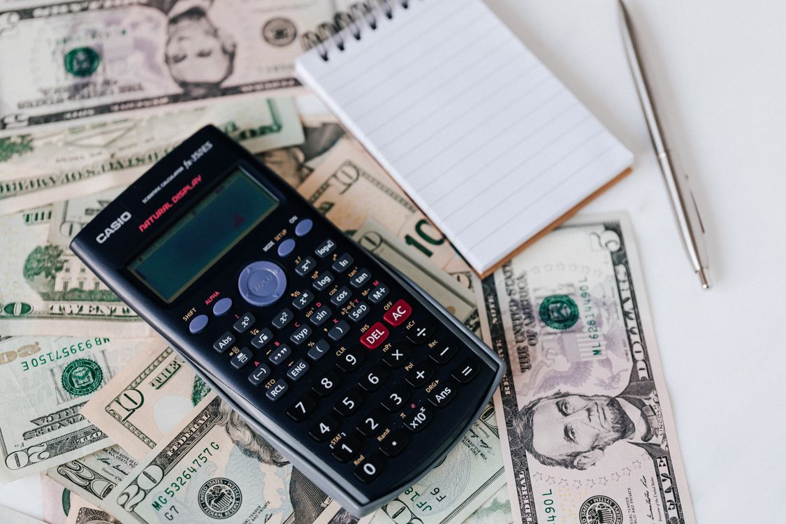 Calculator and notepad on dollar bills for small business technology budget planning