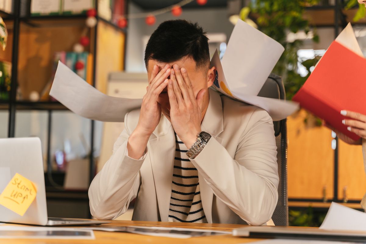 Stressed business professional at desk representing IT downtime cost for small businesses